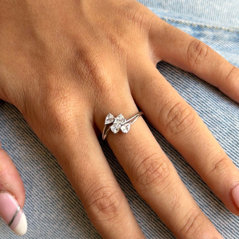 a stunning 925 sterling silver ring featuring accented by four small pear-shaped diamonds aligned horizontally along the band. The polished silver finish enhances the sparkle of the stones, creating a modern, sophisticated look. Adjustable for comfort, this ring is perfect for both special occasions and everyday elegance.