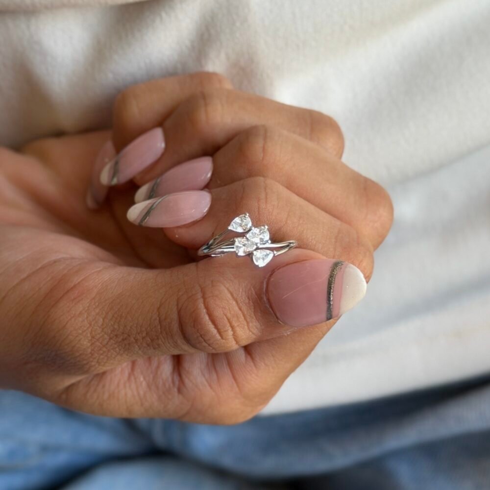 The Elysian Horizon is a stunning 925 sterling silver ring featuring , accented by four small pear-shaped diamonds aligned horizontally along the band. The polished silver finish enhances the sparkle of the stones, creating a modern, sophisticated look. Adjustable for comfort, this ring is perfect for both special occasions and everyday elegance.